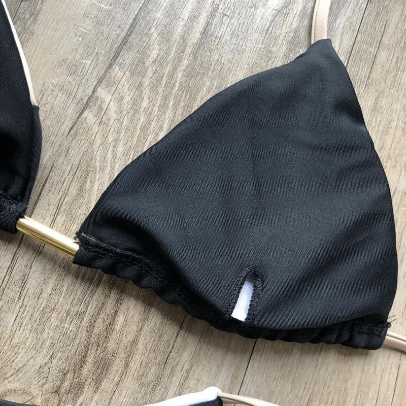Close-up of black bikini top with stylish lace-up design on wooden background.